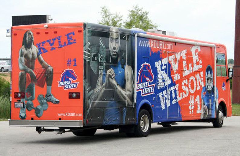 Custom orange and blue Boise State Kyle Wilson experiential marketing truck wrap, featuring large photos of the athlete and the Boise State Broncos logo, demonstrating a good investment for advertising.