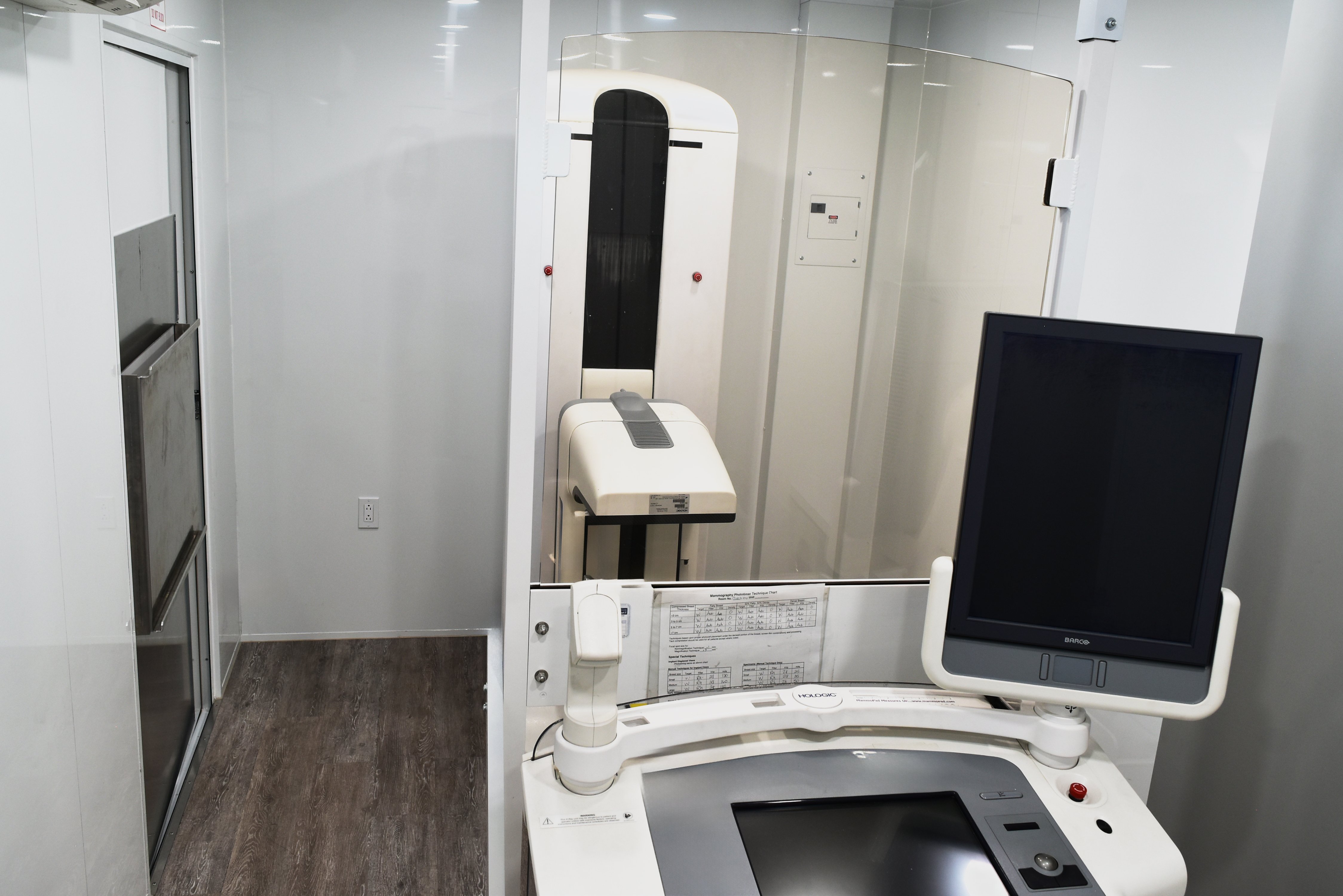 Interior of a mobile mammography unit showing digital imaging equipment, changing room, and storage organization.