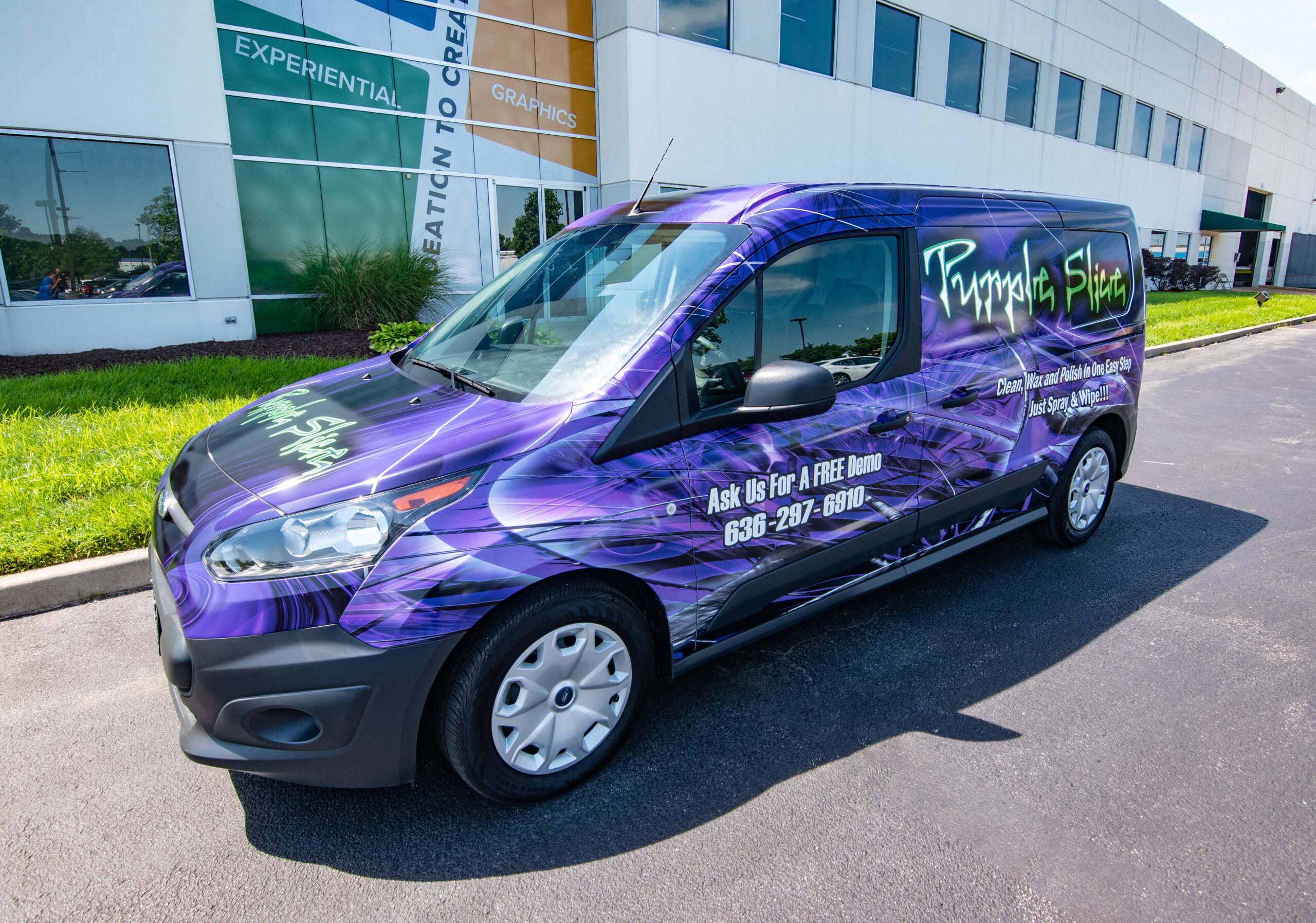 A compact cargo van wrapped with a striking, dark purple and black graphic promoting 'Purple Slic' cleaning product.