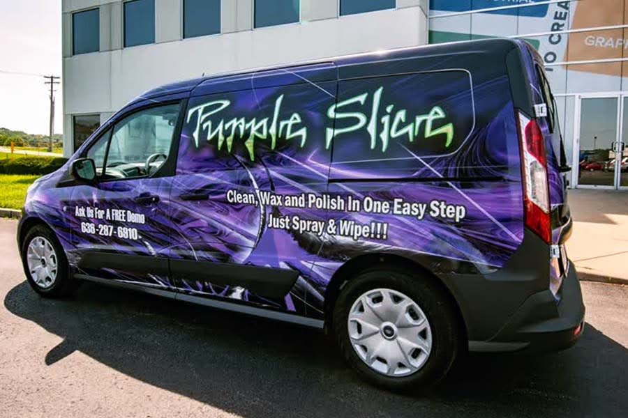 A compact cargo van wrapped with a striking, dark purple and black graphic promoting "Purple Slice" cleaning product.