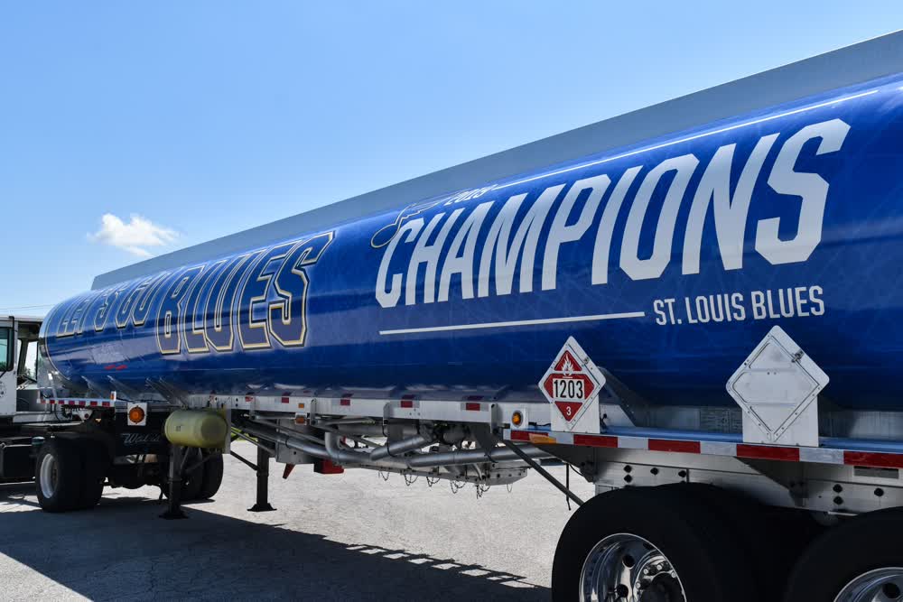 Blue tanker semi-trailer wrapped with "ST. LOUIS BLUES CHAMPIONS" graphic in white and yellow lettering, showcasing specialized sports team fleet graphics for celebratory branding and high-impact regional advertising.