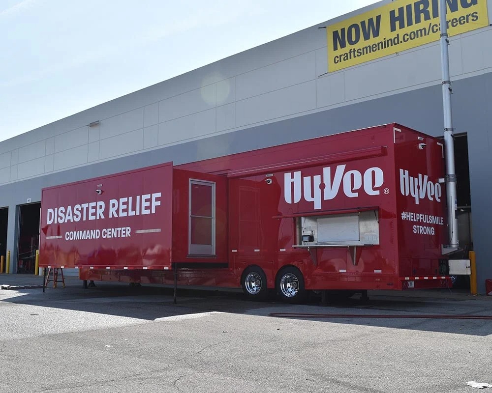 External view of two large tan-colored, custom mobile command center trailers with external generators and ventilation equipment.