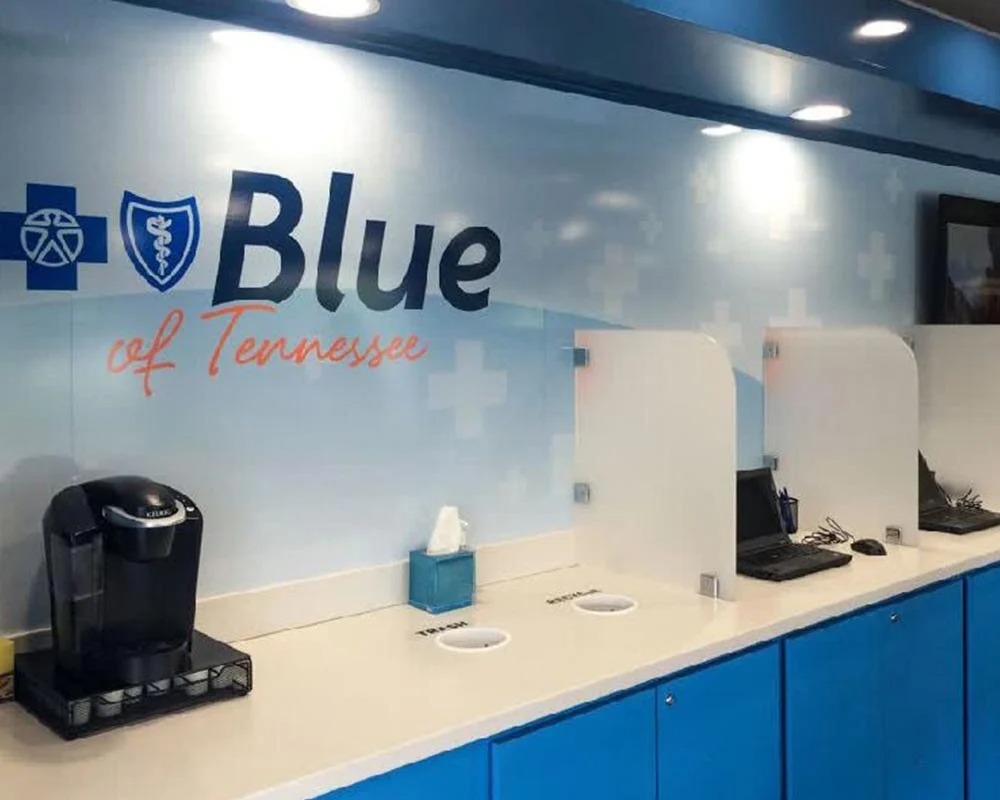 Interior view of the Blue of Tennessee mobile command unit with a coffee maker, two workstations with laptops, and blue cabinets.
