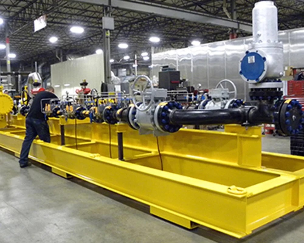 Industrial fabrication gas or water treatment unit inside a shipping container, showing white and blue pressure vessels and yellow piping.