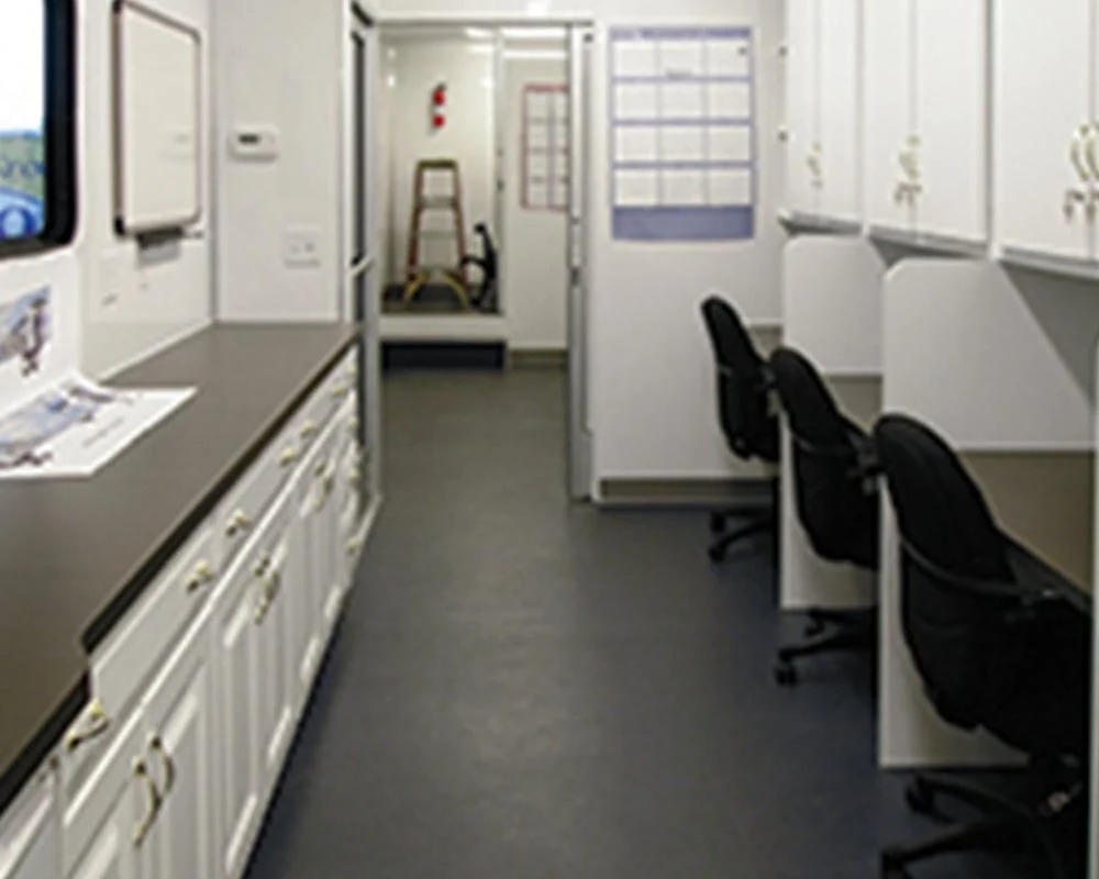 Interior view of the Ameren mobile command center with multiple desks, office chairs, and storage cabinets.