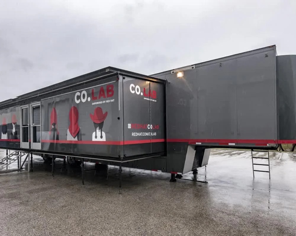 External view of two large tan-colored, custom mobile command center trailers with external generators and ventilation equipment.