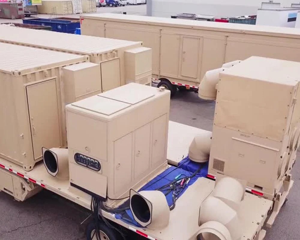 External view of two large tan-colored, custom mobile command center trailers with external generators and ventilation equipment.