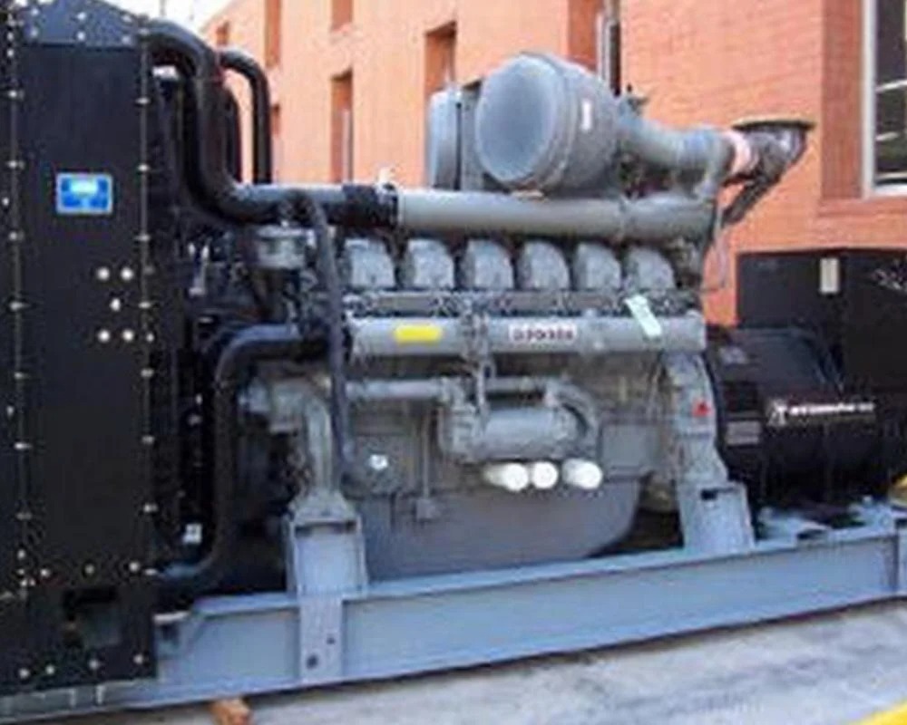 Large gray industrial power generation engine or pump system on a steel base, with complex black piping and a cooling unit.