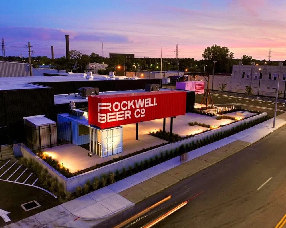 Aerial view of Rockwell Beer Co. bar and patio built with blue and red shipping containers at sunset.