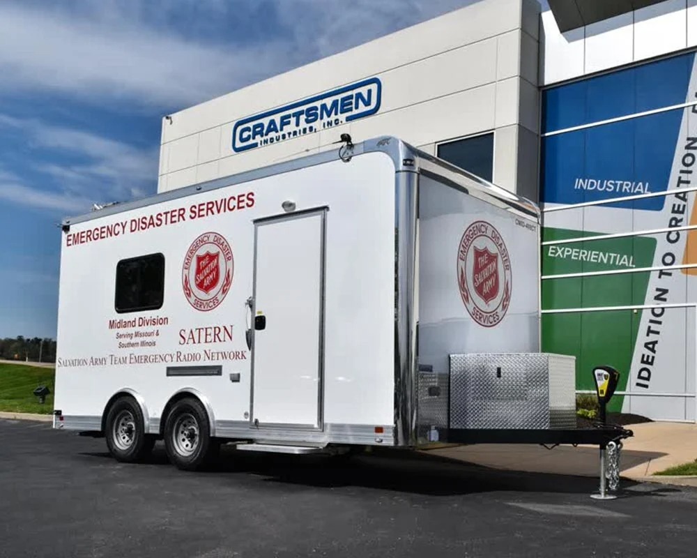 External view of a black Ameren training mobile command center trailer with an extended side panel featuring graphics of workers and a staircase leading to the entrance.