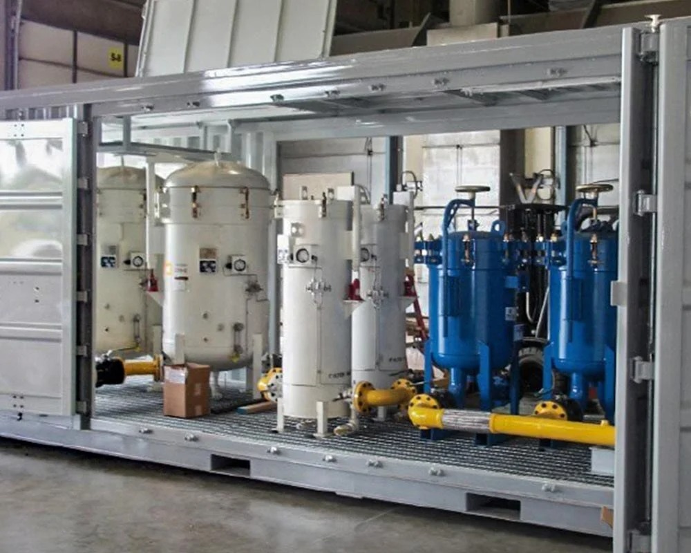 Modular industrial fabrication water or gas processing unit inside a shipping container, featuring large white tanks and smaller blue pressure vessels.