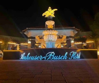 Anheuser-Busch hotel takeover exterior at night with illuminated fountain and eagle/lion griffin logo.