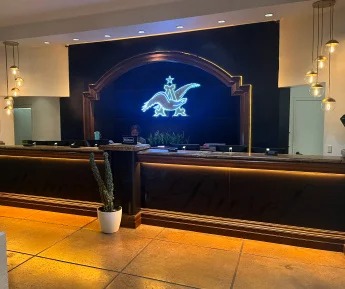 Anheuser-Busch illuminated neon griffin logo sign behind a hotel reception desk at a Super Bowl event takeover.