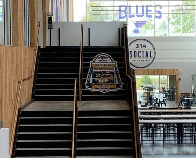 Indoor staircase with floor graphic promoting the St. Louis Blind Hockey Classic 2021 tournament at 314 Social venue.