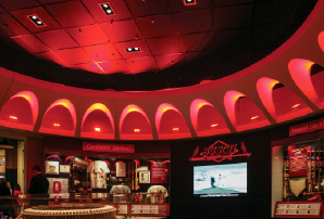 St. Louis Cardinals Museum interior with exhibits, Busch Stadium sign, and memorabilia under dramatic red lighting.