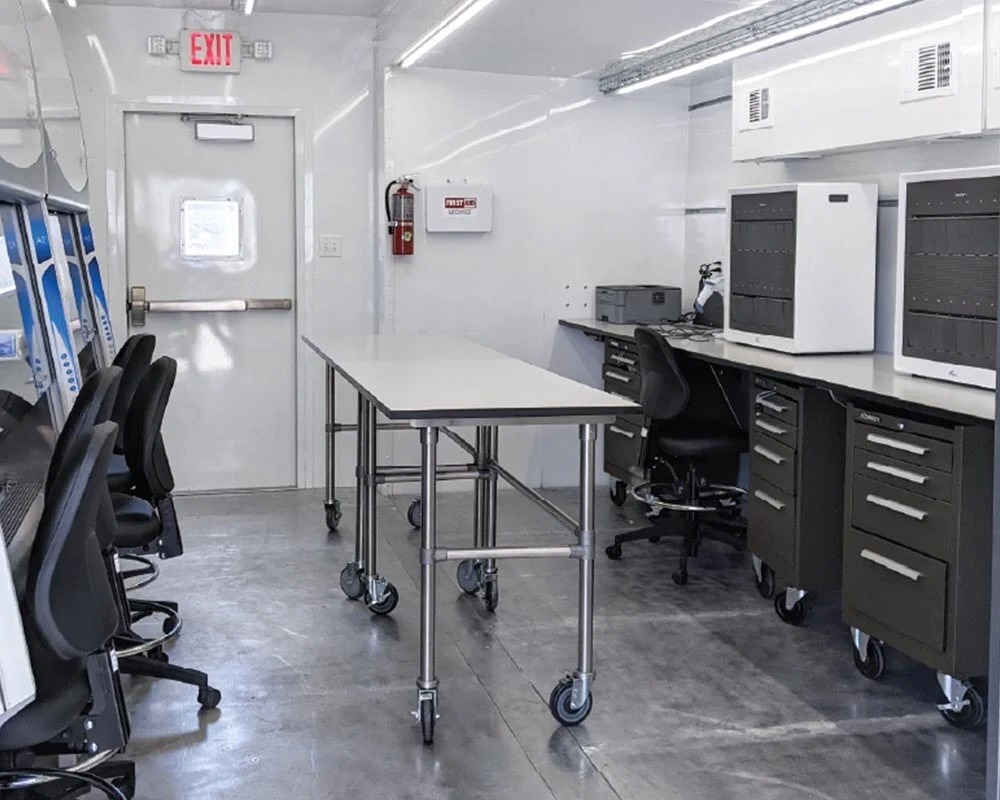 The interior of an Athena mobile lab, showing a long central table, computer workstations, and specialized equipment.
