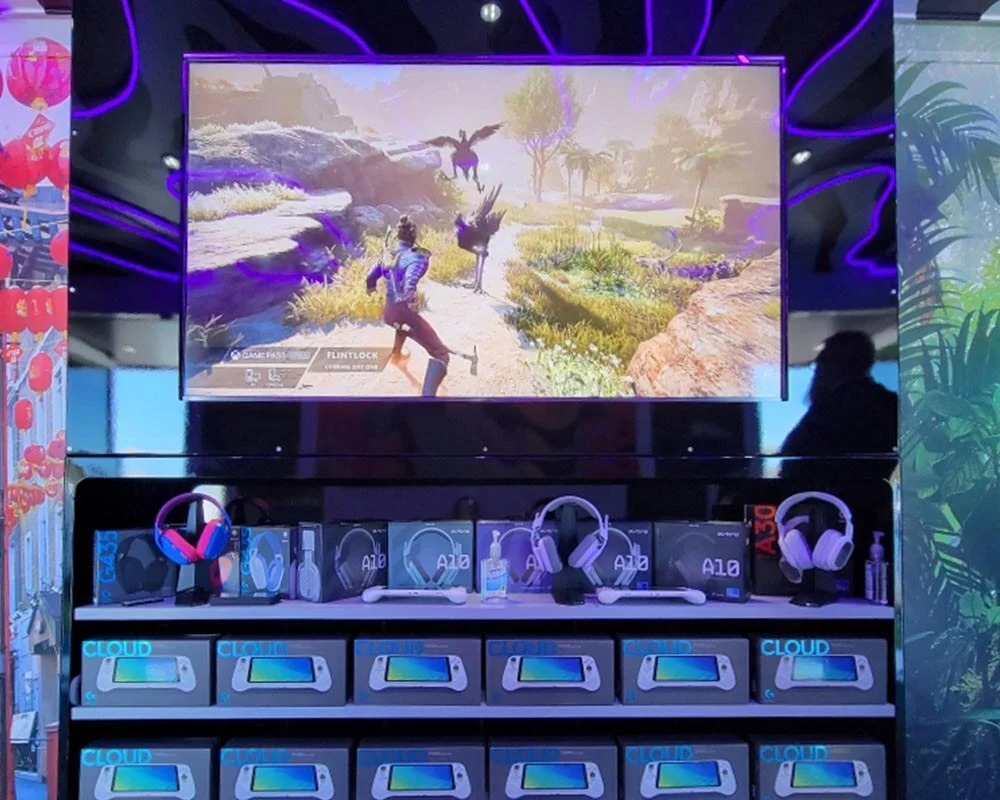Logitech gaming product display featuring A30 and A10 headsets below a screen demonstrating a video game.