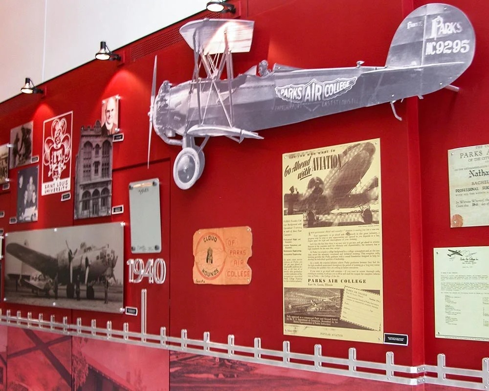 Parks College of Engineering, Aviation and Technology timeline exhibit at Saint Louis University, showcasing a model of a biplane and historical aviation documents from the 1930s and 1940s.