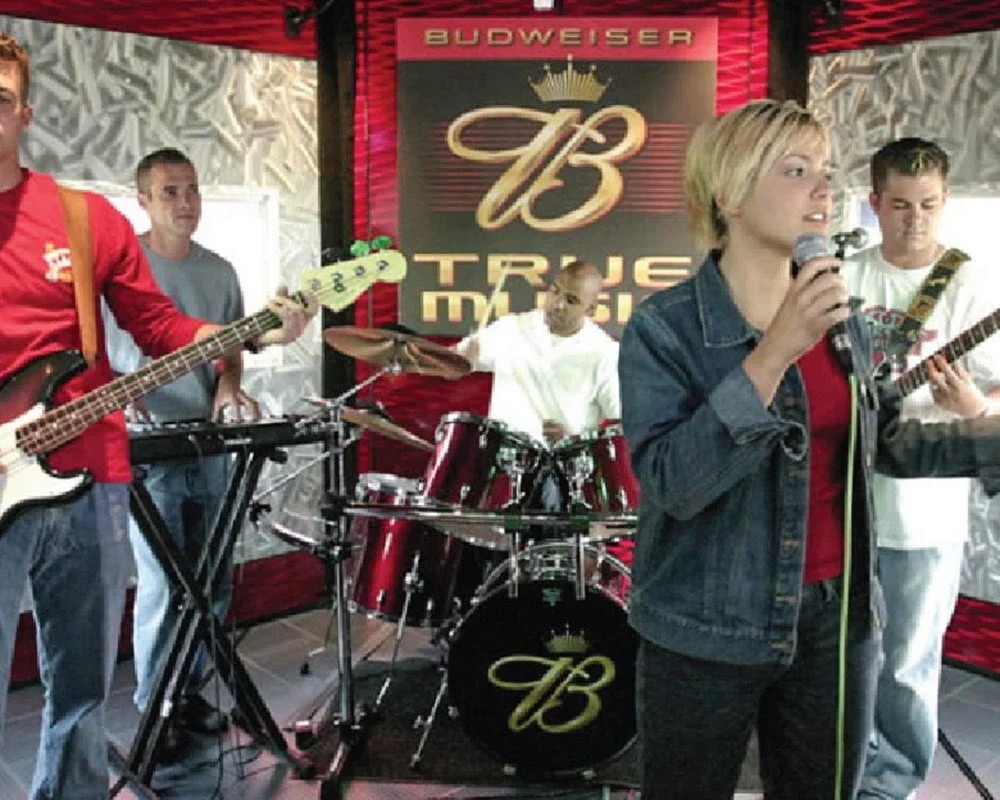 Live band performing on the Budweiser True Music stage, featuring the logo on the drum kit and backdrop.