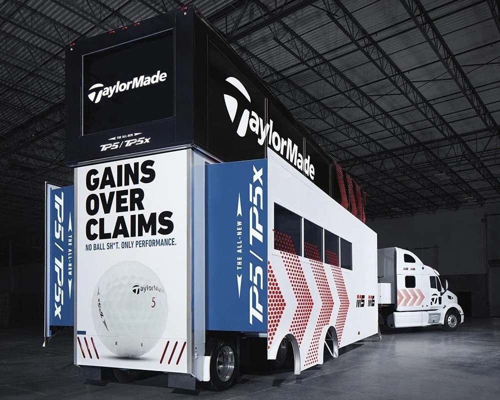 TaylorMade promotional truck featuring TP5 and TP5x golf ball branding with bold 'Gains Over Claims' slogan inside an industrial warehouse setting.