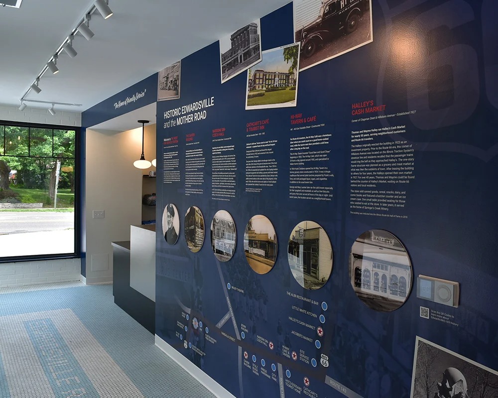 An interior view of the West End Station Route 66 Museum in Edwardsville, featuring a large navy-blue wall graphic exhibit titled