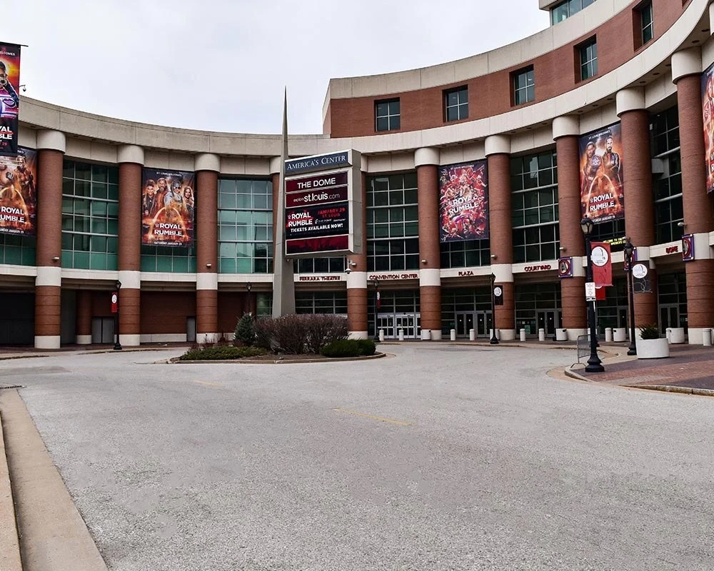 Curved brick and glass exterior of The Dome at America's Center with multiple large WWE Royal Rumble event banners.