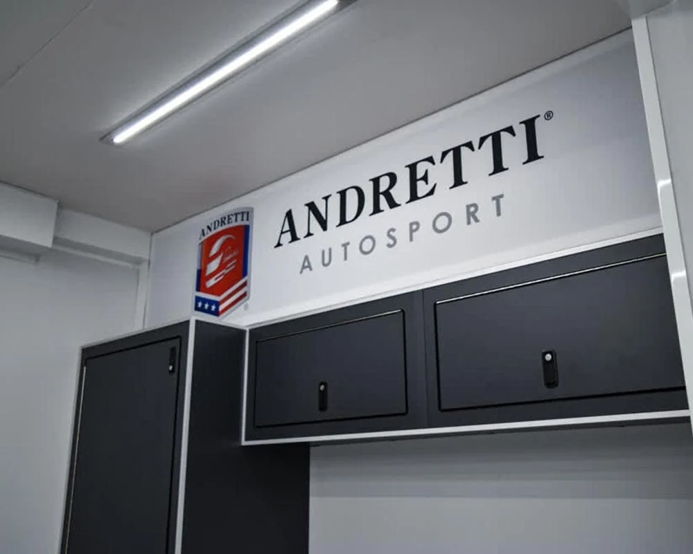 Close up of the Andretti Autosport logo and branding inside a motorsports race car trailer above storage cabinets