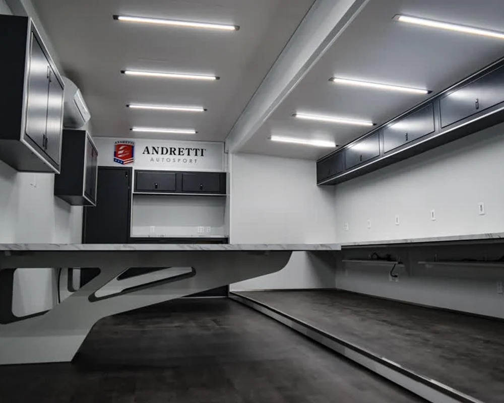 Andretti Autosport motorcycle trailer interior workshop with custom black cabinets, marble countertop, and fluorescent strip lighting.