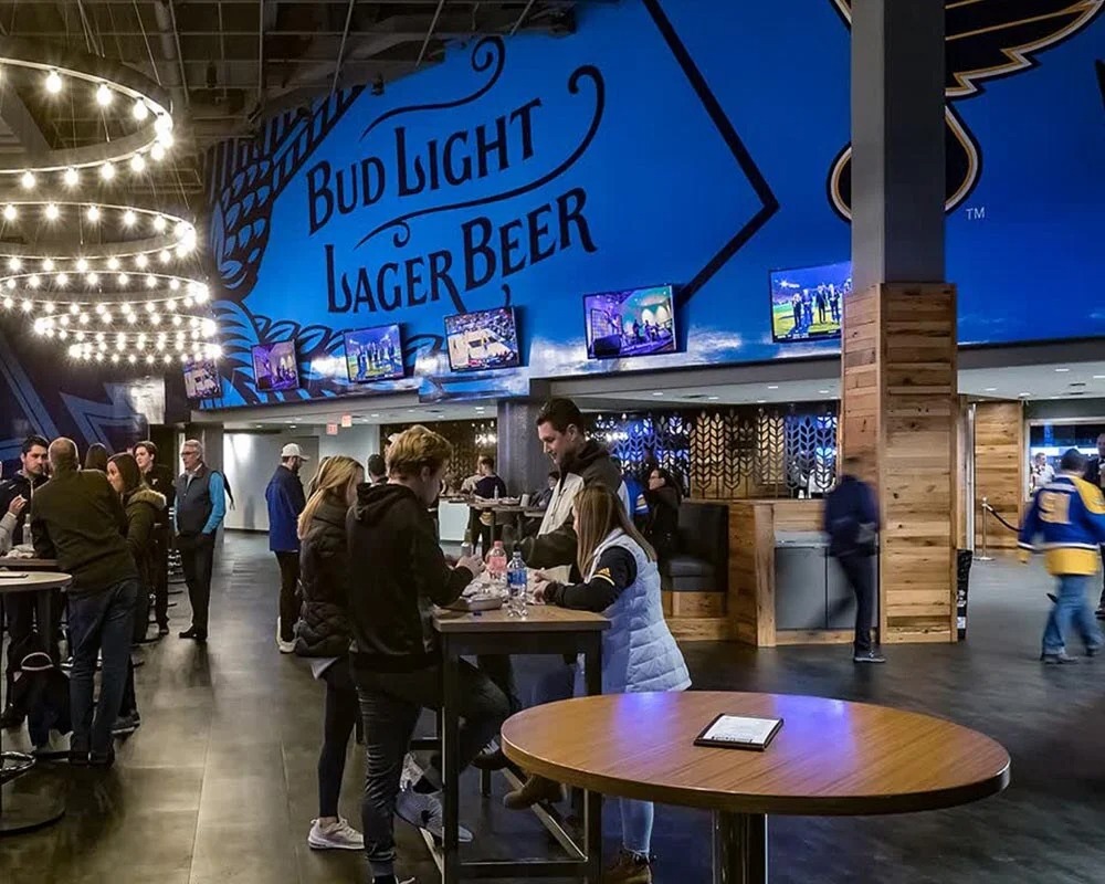 An image of a lively indoor stadium or arena bar area with a large, blue wall graphic reading 