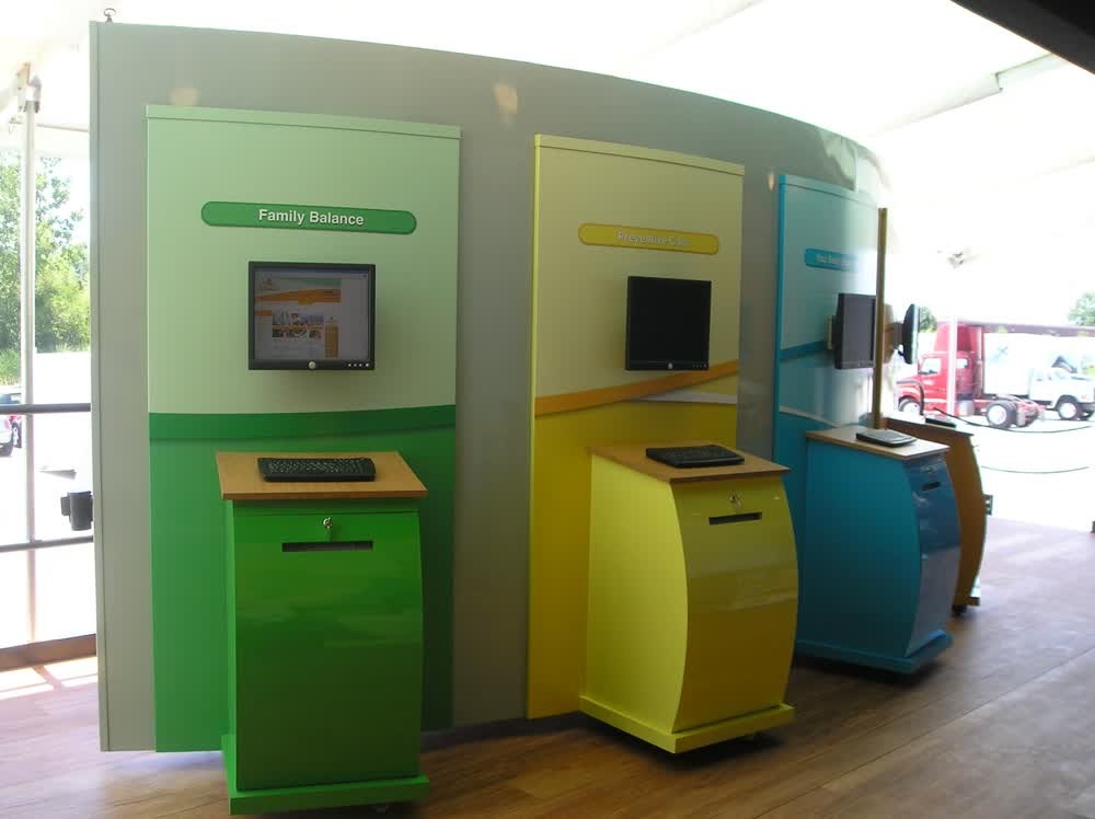 Three bright, interactive health kiosks inside a Discovery Health mobile unit. The health education stations are labeled