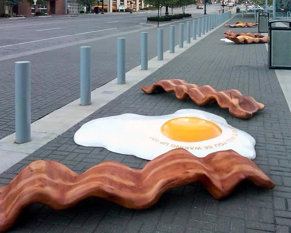 Giant fiberglass eggs and bacon props installed on a city sidewalk for a fun experiential event display.