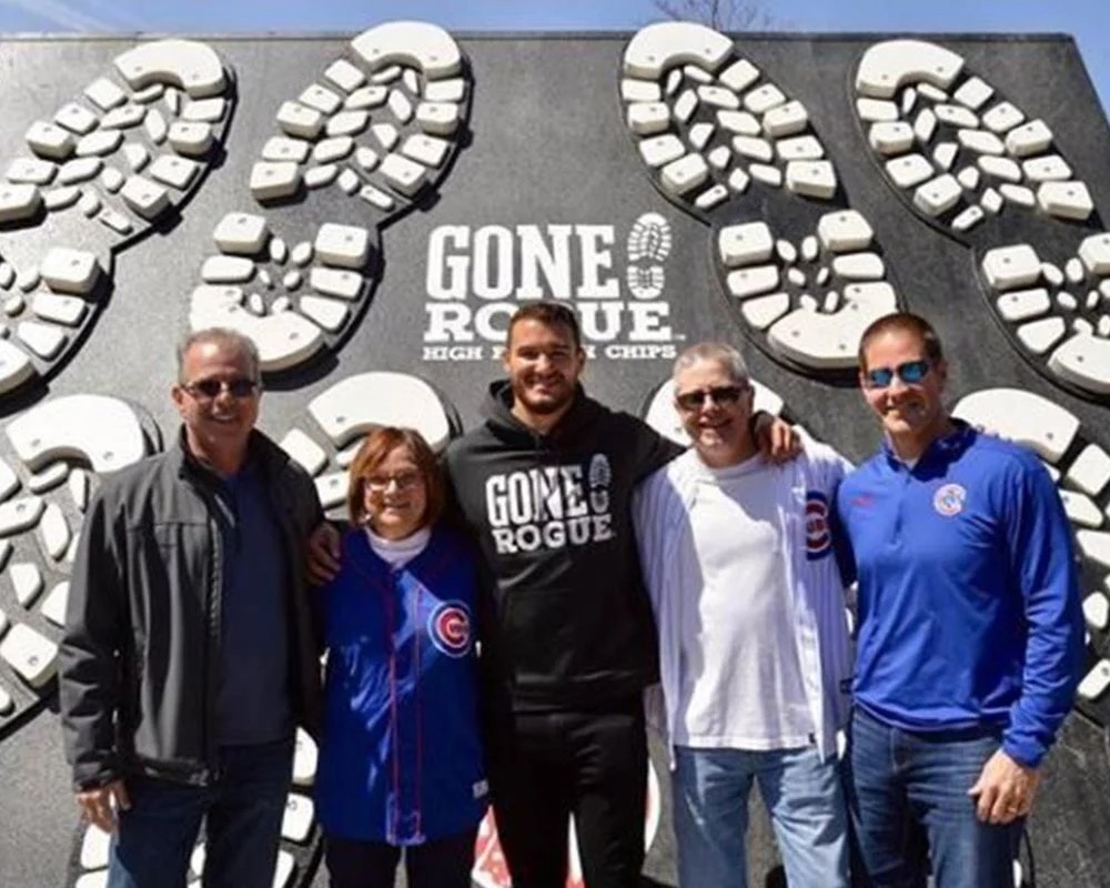 Group of fans posing in front of the Gone Rogue high protein chips wall with giant boot sole graphics.