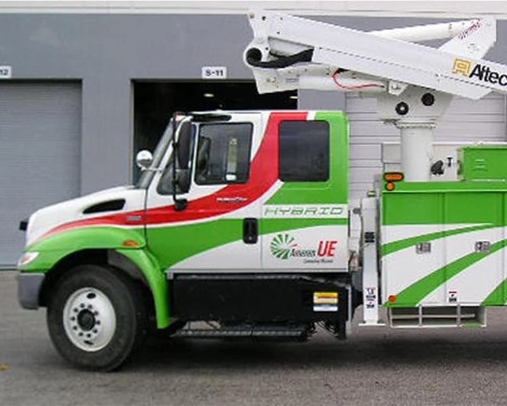 White commercial utility bucket truck with a bright green and red graphic wrap, featuring the text