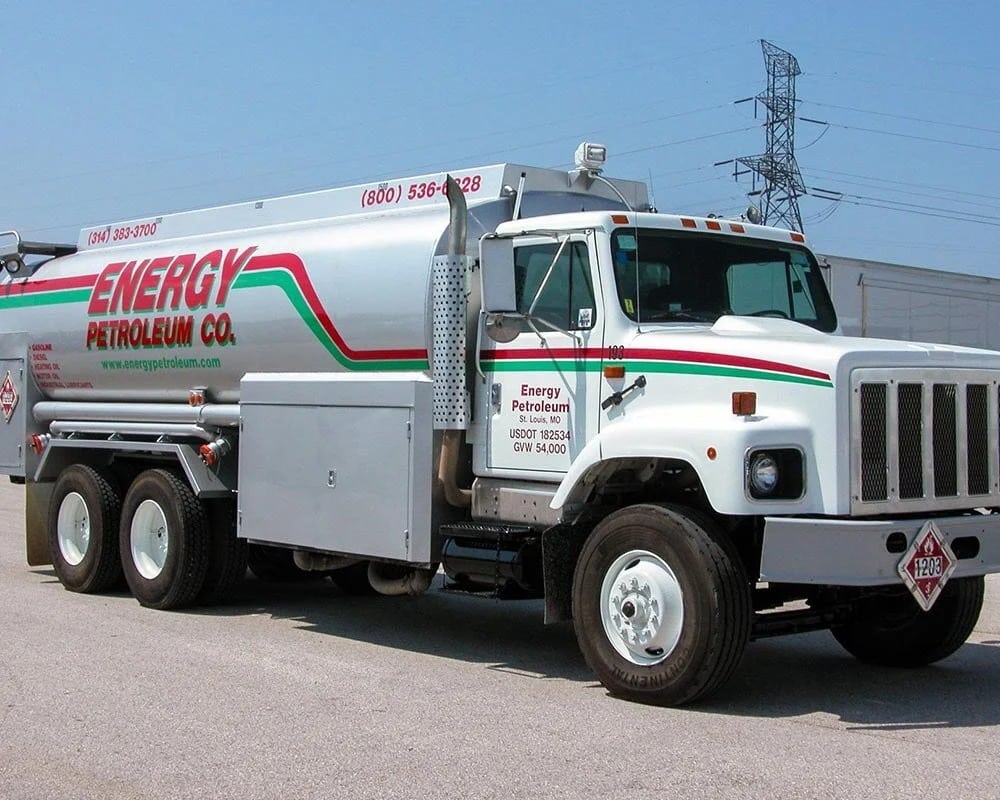 White commercial tanker truck for Energy Petroleum Co. with a silver tank, featuring a red and green stripe graphic, phone number (800) 536-6328, and 'St. Louis, MO' address, parked outside on a clear day.