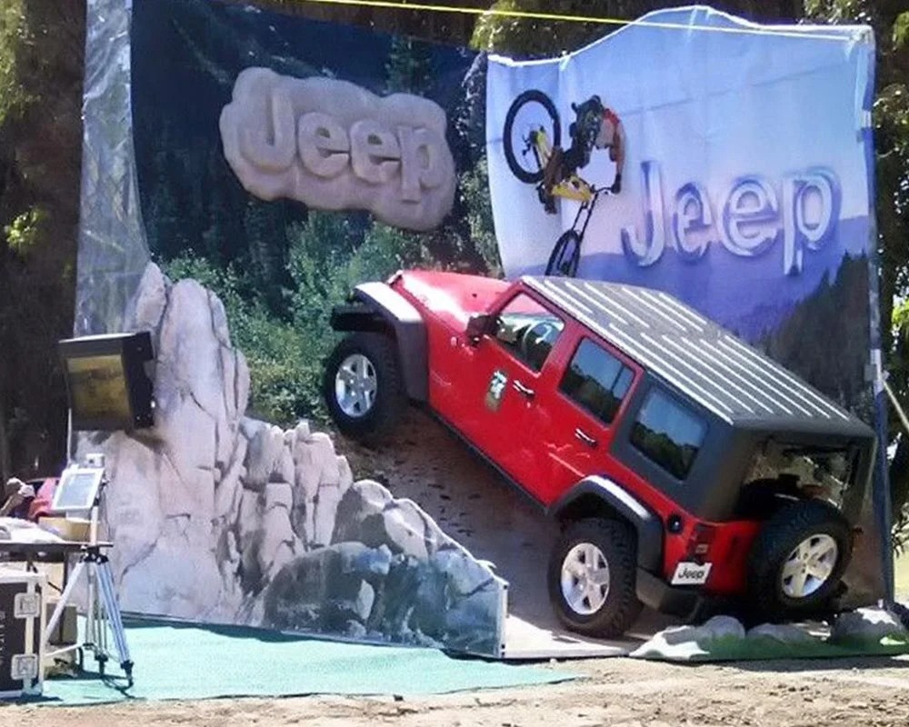 Red Jeep Wrangler mounted on a faux rock climbing terrain display for an off-road experiential event.