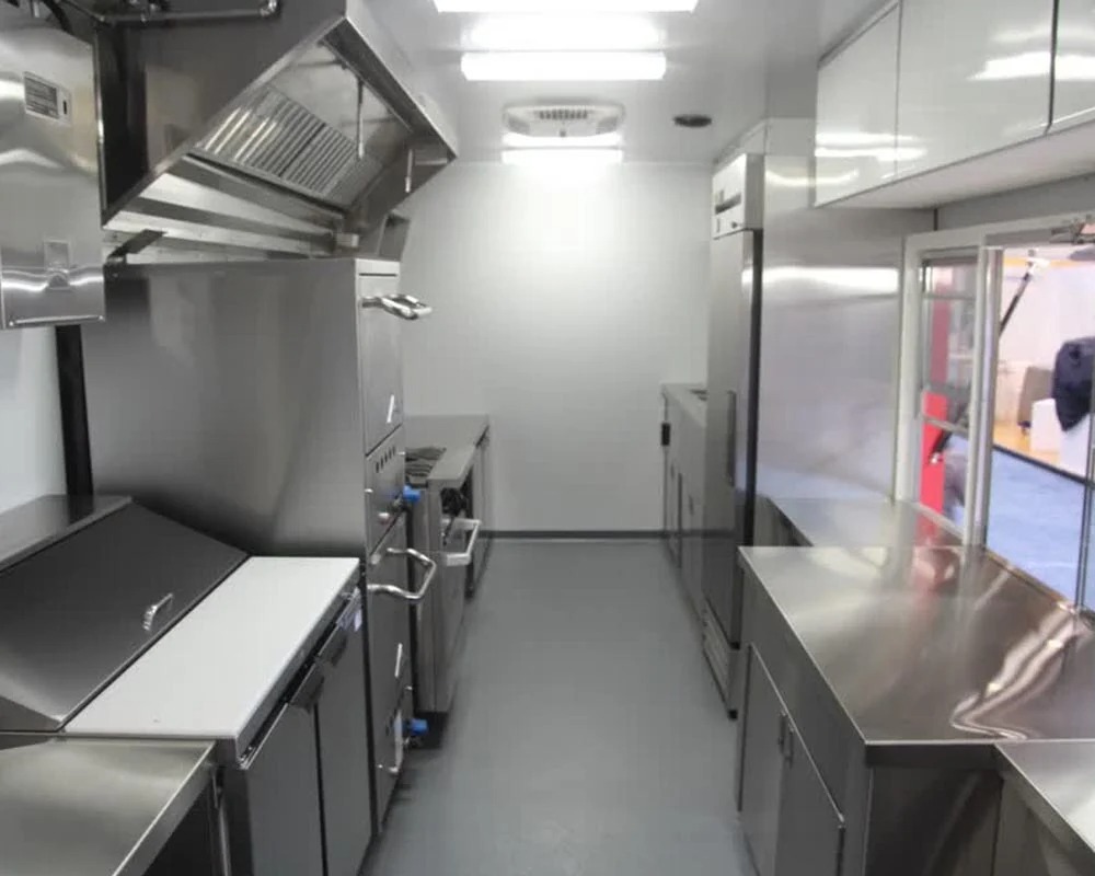 Bright, clean stainless steel kitchen interior of a custom food truck built by professional food truck builders, featuring commercial appliances and counters.
