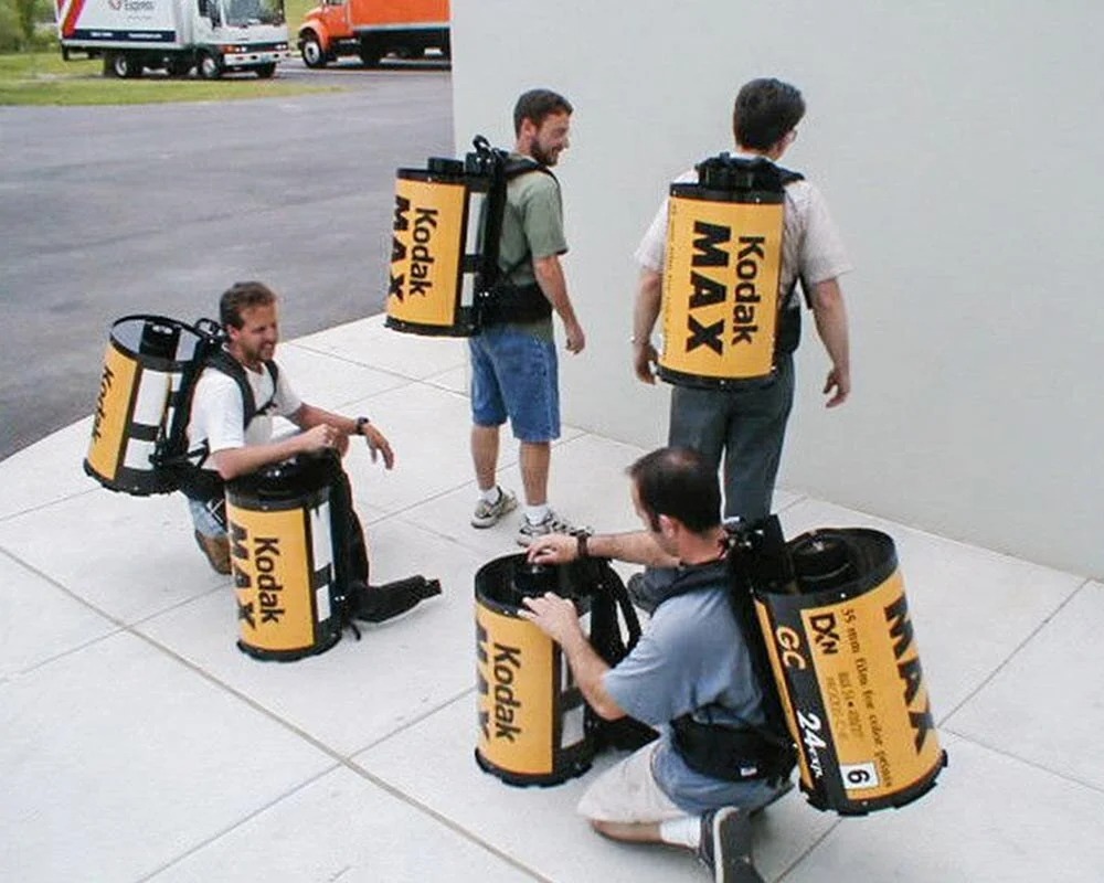 kodak max experiential event elementsƄFour brand ambassadors wearing giant Kodak Max film canister backpacks for an experiential event promotion.