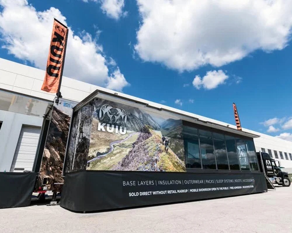Kuiu mobile showroom trailer with a mountain scene graphic, promoting hunting gear, base layers, and outerwear.