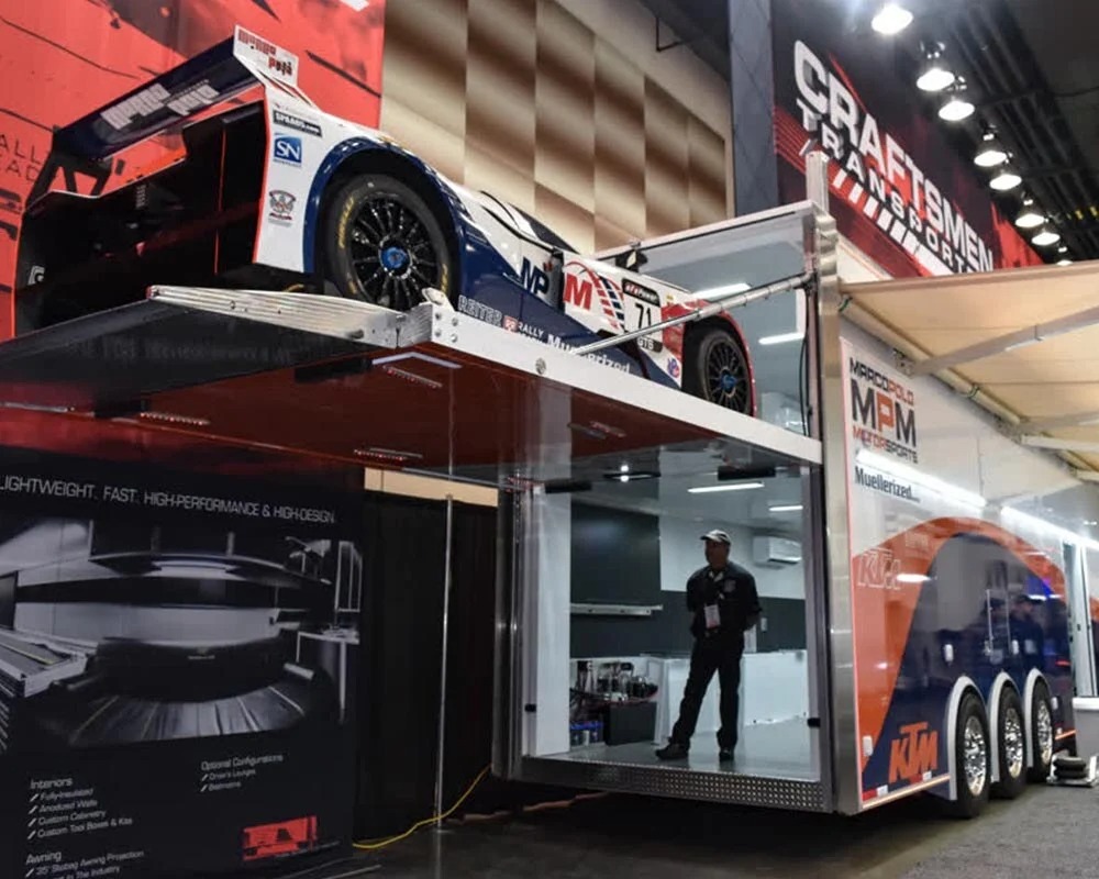 Marco Polo Motorsports motorcycle trailer with two-level race car lift, featuring MPM and KTM branding.