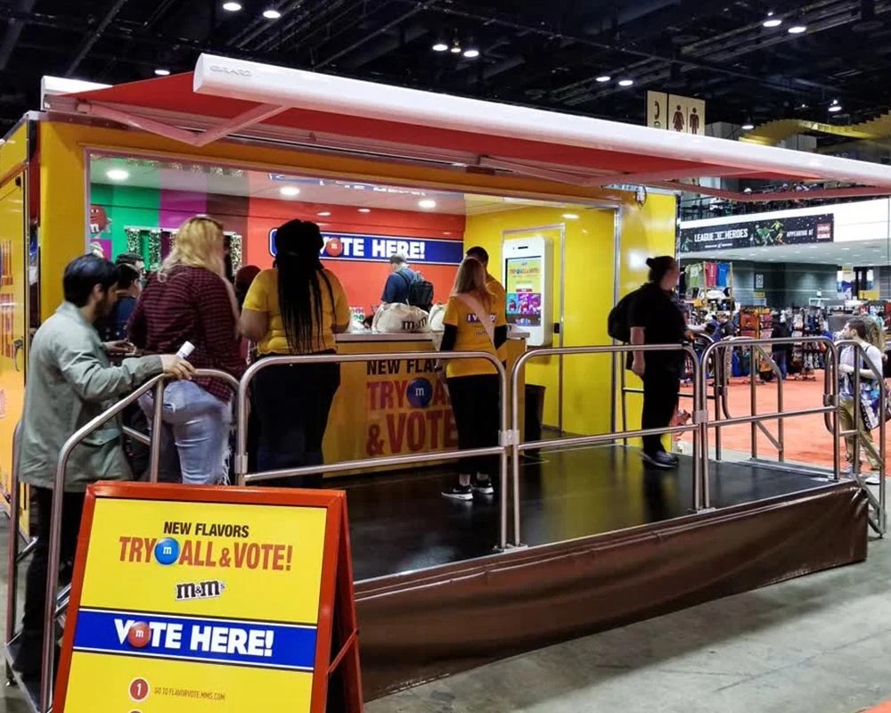 Crest promotional event trailer shaped like a toothpaste tube with people gathered around for a brand marketing activation outdoors.