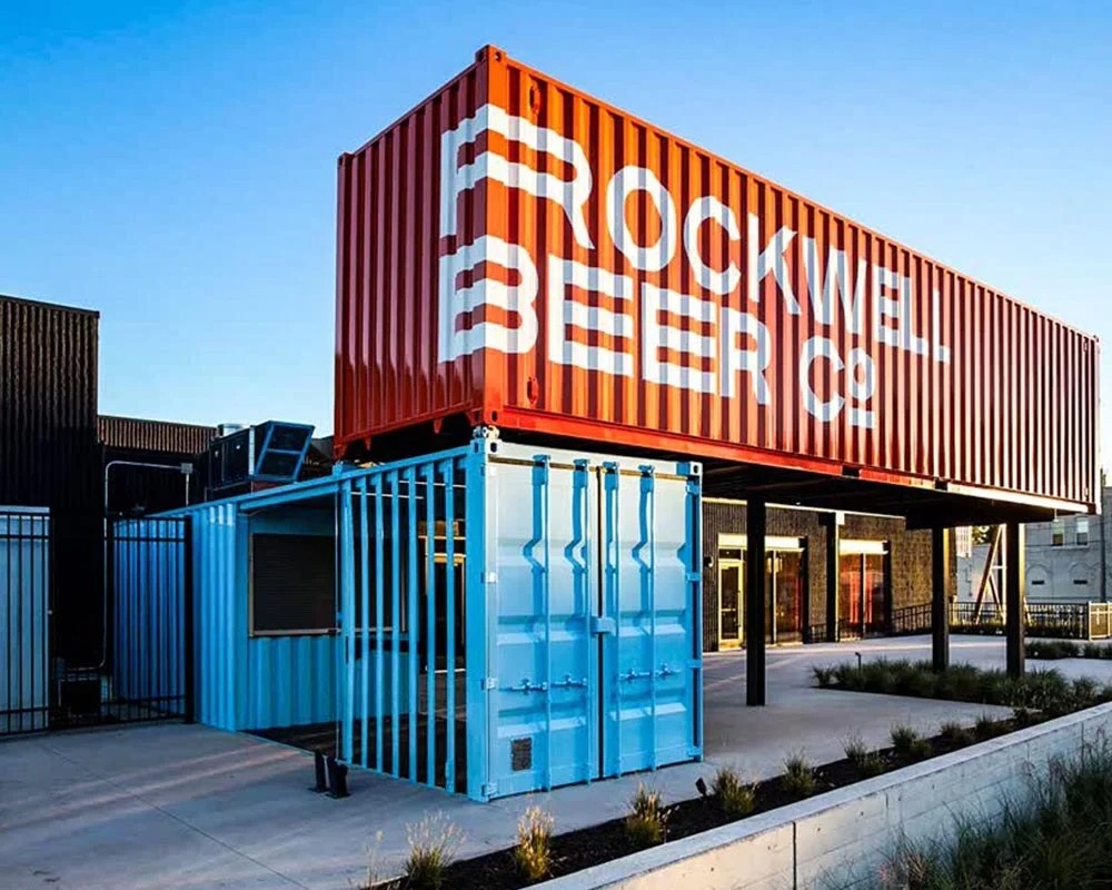 Rockwell Beer Co. shipping container conversion into a multi-level brewery and beer hall with a bright red upper container and light blue service container.