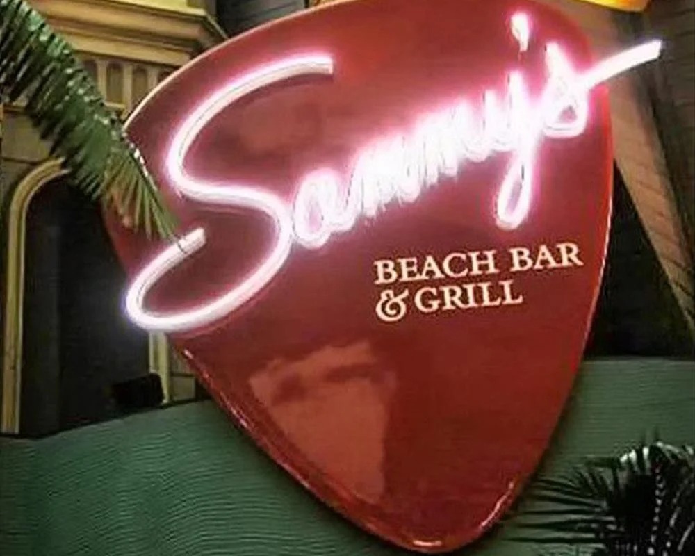 Sammy's Beach Bar & Grill neon sign shaped like a giant guitar pick for an experiential event.