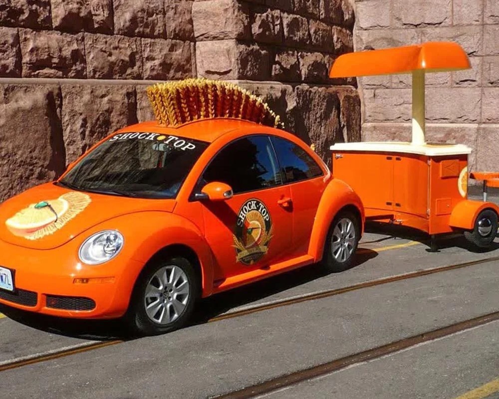 Orange Shock Top branded VW Beetle with wheat mohawk and matching beverage trailer for an experiential event.
