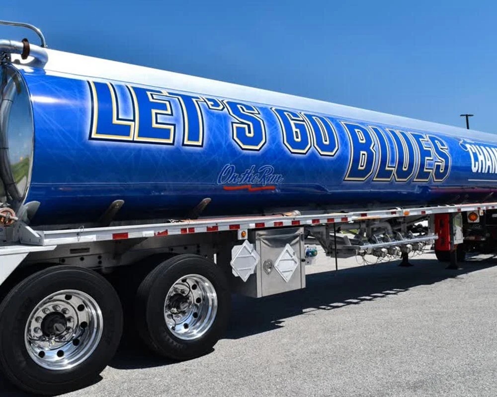 Custom vinyl graphics on a semi tanker truck reading Lets Go Blues in blue and gold lettering