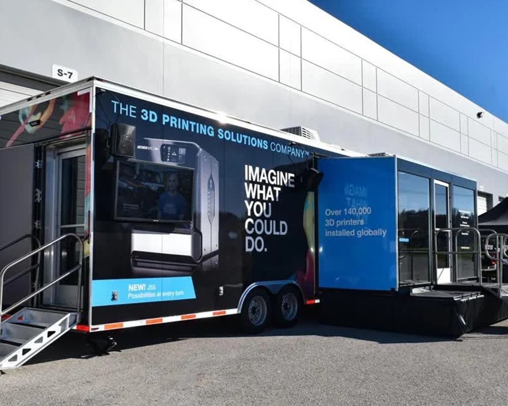 Black Stratasys mobile showroom trailer exterior showcasing the J55 3D printer and featuring the slogan