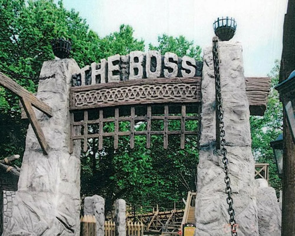 The Boss wooden roller coaster entrance archway with large stone pillars and a carved wooden sign.